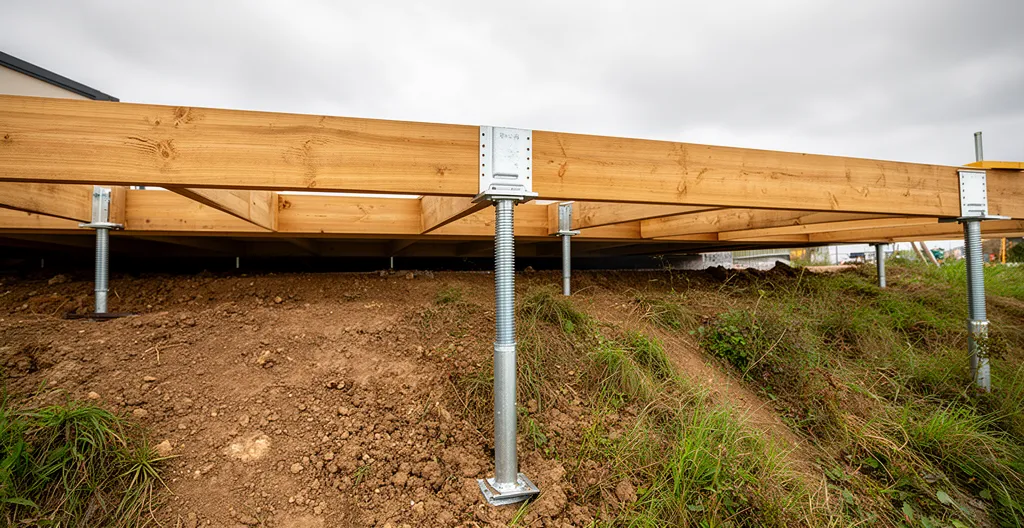Structure de terrasse sur pilotis en cours de construction avec plots réglables et lambourdes visibles